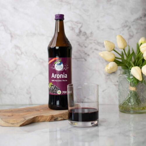 Aronia juice in glass with bottle